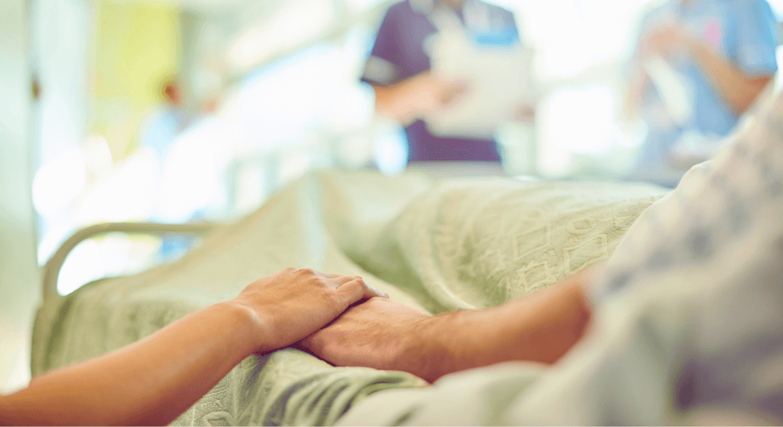 Billede af to hænder, der holder hånd i en hospitalsseng