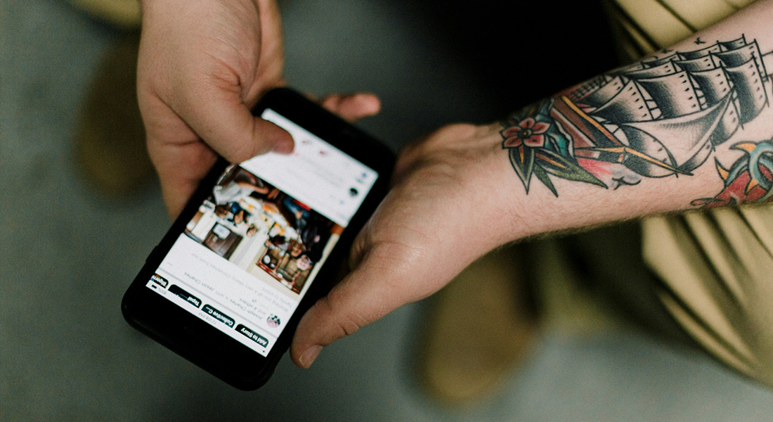 Tattooed man looking at smartphone. Tattooed man looking at smartphone.